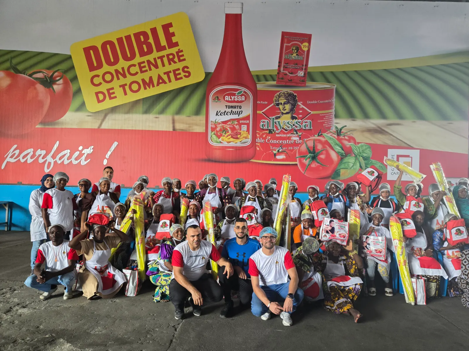 Rencontre du groupe avec les commerçants partenaires, sous l’affiche du double concentré de tomates Alyssa